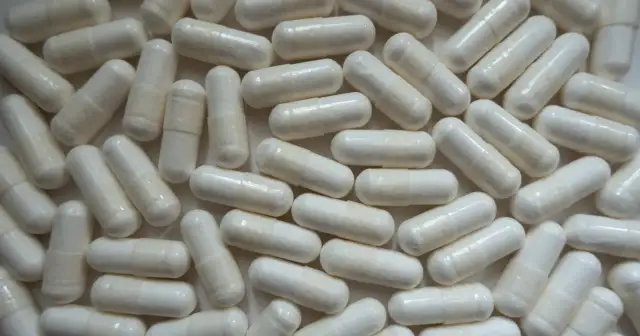 Mnóstwo białych kapsułek z cytrynianem magnezu, które pomagają w regeneracji i wspierają zdrowie.