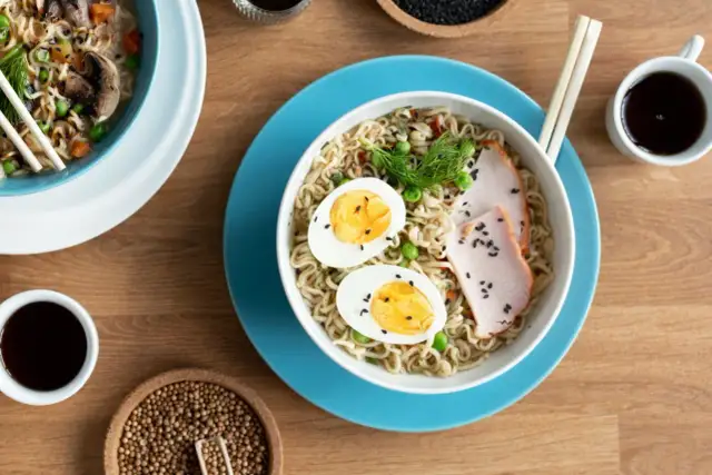 Pyszny tantanmen ramen z jajkiem, plastrami mięsa i zielonym groszkiem. Idealny na szybki, sycący posiłek.