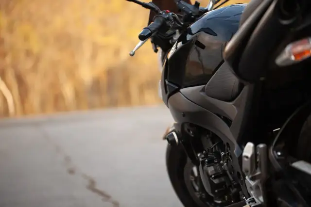 Czarny motocykl na tle jesiennego krajobrazu. Zastanawiasz się, jaki przebieg dla motocykla jest duży? Ten wygląda na gotowy na wiele przygód.