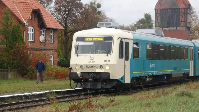 Pociąg Arriva z napisem "POCIĄG SPECJALNY" na tle ceglanego budynku i wieży.