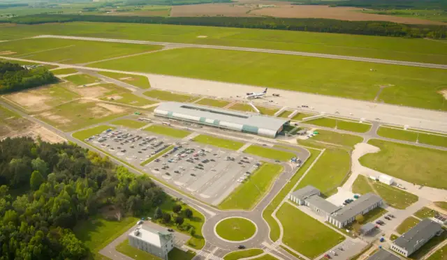 Widok z lotu ptaka na lotnisko z terminalem, parkingiem i pasami startowymi. Ile jest pasów startowych w Warszawie? Na tym zdjęciu widać dwa pasy.