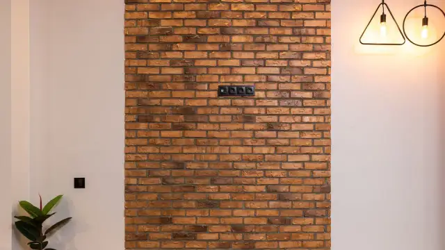 Fragment ściany z cegły dekoracyjnej z gniazdkami elektrycznymi.