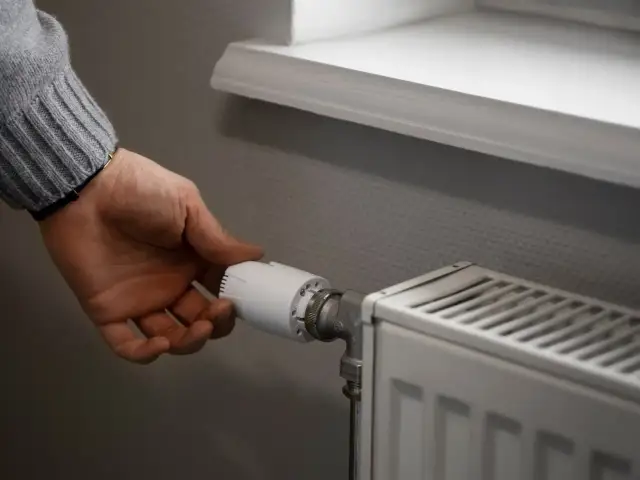 Dłoń reguluje zawór grzejnika, pokazując, jak zakręcić grzejnik bez termostatu.