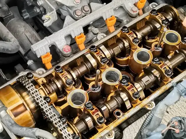 Silnik z otwartą pokrywą zaworów, widoczne wałki rozrządu, wtryskiwacze i łańcuch rozrządu. To dobry sposób na uszczelniacze zaworowe.