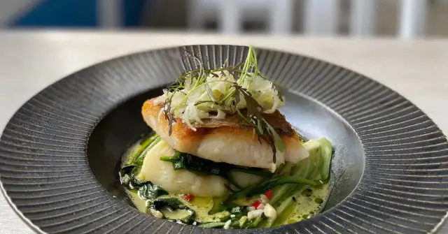 Smażony filet rybny z puree ziemniaczanym i zielonymi warzywami w sosie.