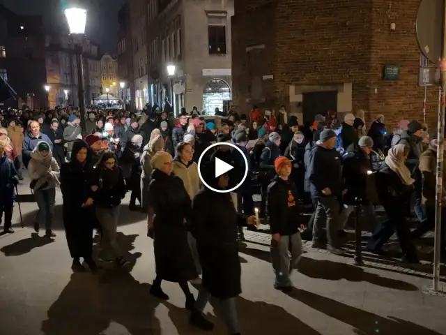 Tłum ludzi idzie ulicą nocą, trzymając świece. To uroczysta chwila, kiedy jest droga krzyżowa.