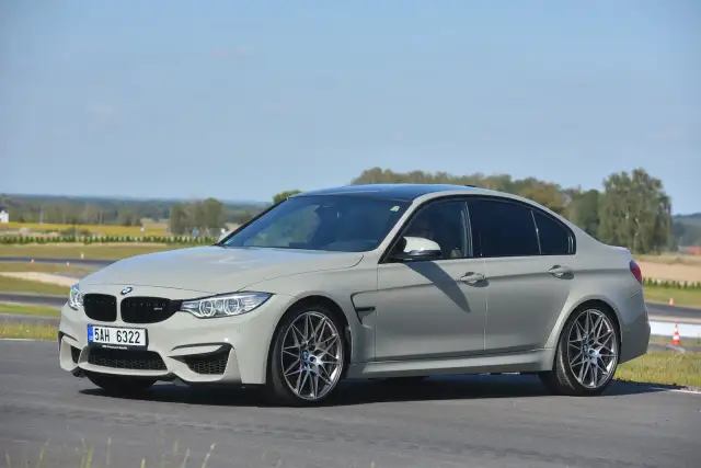 Szare BMW M3 F80 na torze wyścigowym, z widocznym kierowcą.