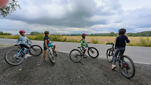 Dzieci na rowerach, szukają idealnego roweru na 140 cm wzrostu. Na tle pól i chmur.