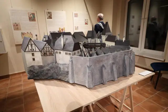 Model zamku z szarymi dachami i kamiennymi murami na drewnianym stole.