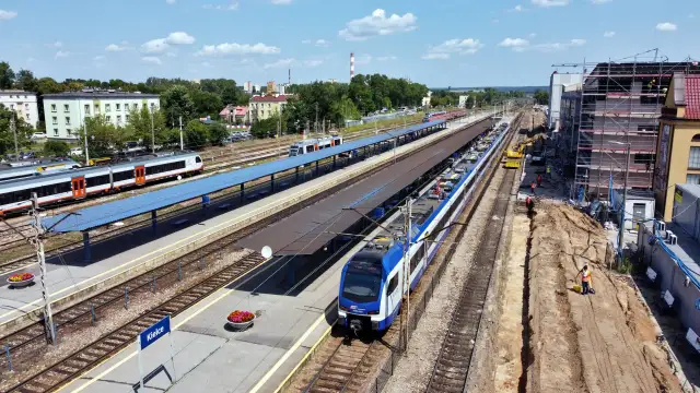 Widok z góry na dworzec kolejowy w Kielcach z pociągami na torach i placem budowy.
