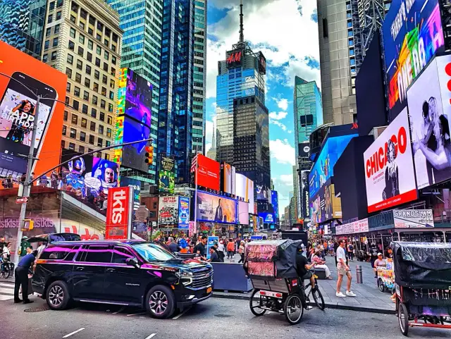 Times Square w Nowym Jorku z neonami, ludźmi i rikszami.