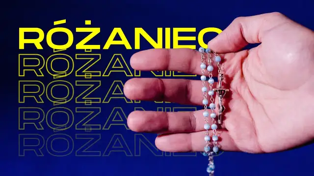 Dłoń trzymająca różaniec z niebieskimi paciorkami i krzyżem.