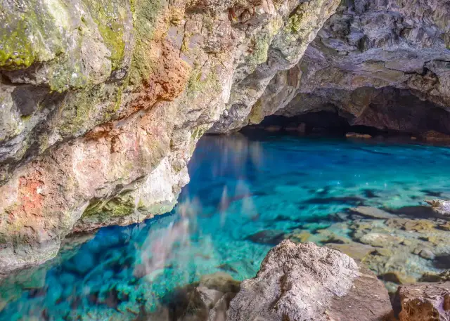 Jaskinia Zeusa w Turcji, z krystalicznie czystą, turkusową wodą odbijającą skalne ściany.