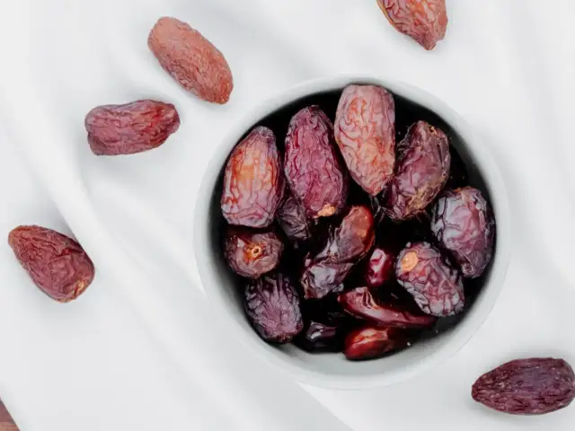 Daktyle w miseczce i obok. To naturalne słodycze, które mają najwięcej kalorii, idealne na szybki zastrzyk energii.