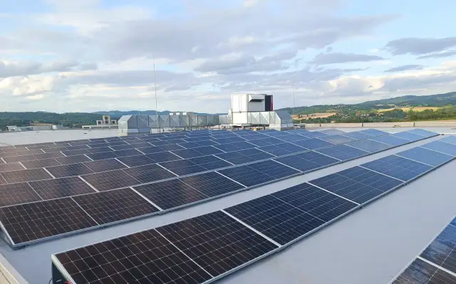 Duże panele fotowoltaiczne na dachu, obok systemów wentylacyjnych i agregatu prądotwórczego, zapewniające niezawodność energetyczną.