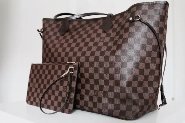 Duża torebka Louis Vuitton w kratkę, obok mniejsza kosmetyczka. Klasyczny wzór Damier Ebene.