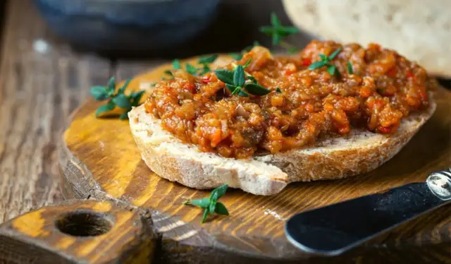 Pyszna pasta z bakłażana na chrupiącym pieczywie, ozdobiona świeżymi ziołami. Idealna na przekąskę.