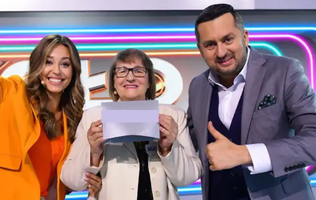 Trzy osoby: kobieta w pomarańczowej marynarce, starsza kobieta z kartką i mężczyzna w garniturze pokazujący kciuk w górę.