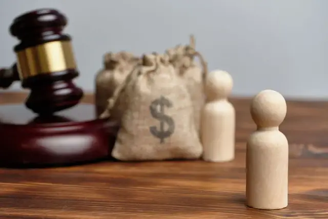 Młot sędziowski, sakiewki z pieniędzmi i drewniane figurki symbolizują obecność uczestników na rozprawie o stwierdzenie nabycia spadku.