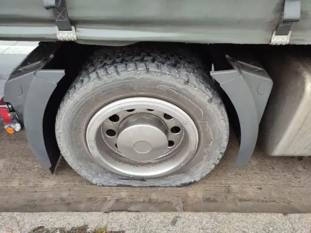 Płaska opona ciężarówki pod błotnikiem.