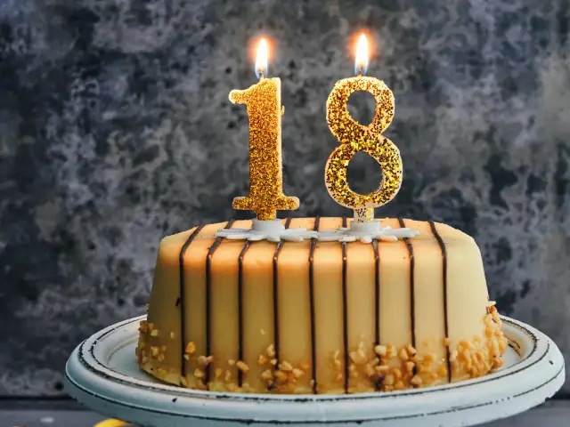 Złote świeczki w kształcie cyfr 1 i 8 na torcie urodzinowym.