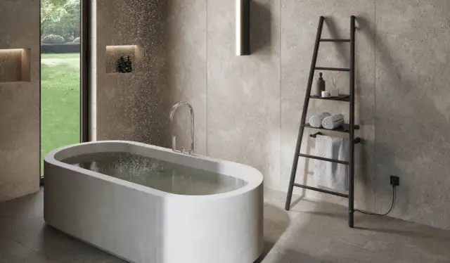 Nowoczesna łazienka z wanną i czarnym, elektrycznym grzejnikiem drabinkowym, na którym wiszą ręczniki.