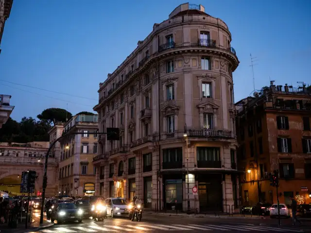 Wieczorny Rzym, ruchliwe skrzyżowanie. Zastanawiasz się, gdzie najlepiej nocleg w Rzymie? To miasto oferuje wiele opcji.