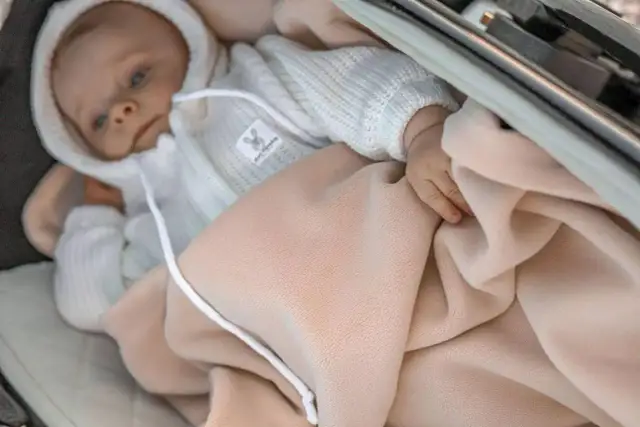 Niemowlę w wózku otulone beżowym śpiworkiem. Idealny na chłodniejsze dni, sprawdzi się od jakiej temperatury śpiworek do wózka.