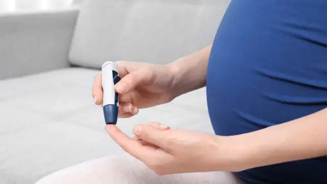 Kobieta w ciąży wykonuje pomiar glukozy glukometrem. Dba o swoją krzywą cukrową.