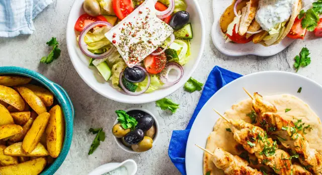 Pyszna kuchnia cypryjska: sałatka grecka, souvlaki z kurczaka, pieczone ziemniaki i oliwki.