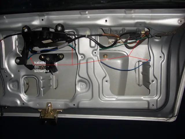 Wnętrze drzwi samochodu z widocznym siłownikiem centralnego zamka i okablowaniem.