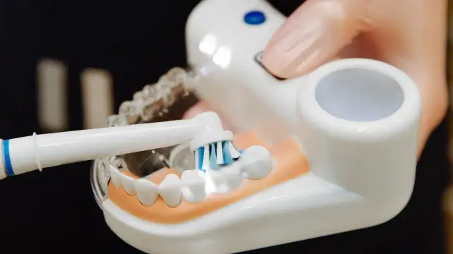 Demonstracja, jak myć zęby szczoteczką elektryczną na modelu. Widać główkę szczoteczki z pastą na zębach.