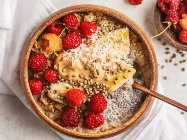 Pyszne śniadanie z chia: owsianka z malinami, bananem, masłem orzechowym i wiórkami kokosowymi.