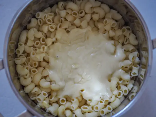 Gęsty, kremowy sos serowy otula makaron w garnku, tworząc pyszny makaron mac and cheese.