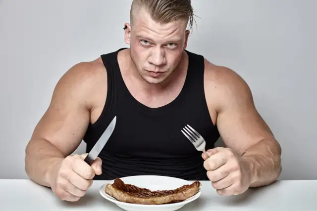 Mięśniak z determinacją wpatruje się w stek, gotowy na wyzwanie, jak szybko przytyć.