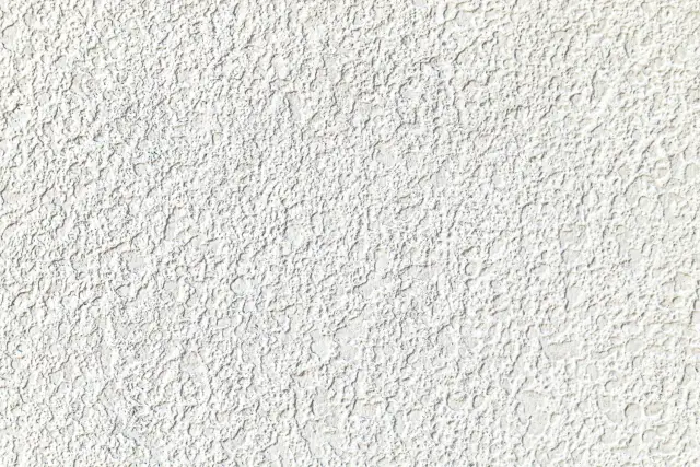 Tekstura białego tynku silikonowego z widocznymi nierównościami.