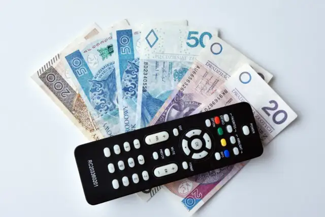Pilot do telewizora leży na stosie banknotów. Czy trzeba płacić abonament żeby wygrać w RMF FM?