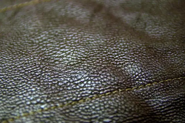 Zbliżenie na fakturę ciemnobrązowej skóry. Real leather to naturalny, trwały materiał, który pięknie się starzeje. Widoczny delikatny szew.