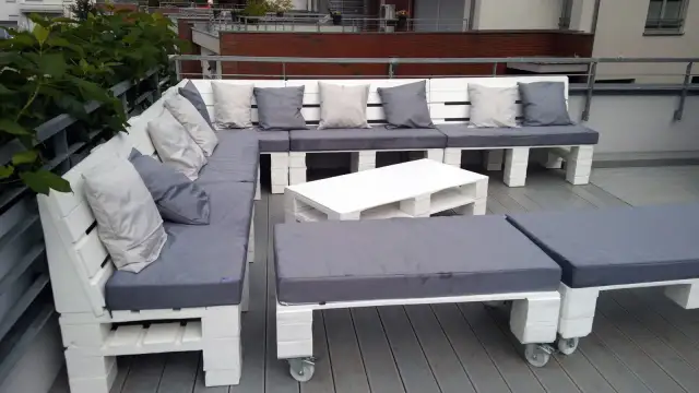 Narożna sofa i stolik kawowy z palet, pomysły na meble z palet. Szare poduszki dodają przytulności.