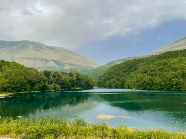 Malownicze jezioro Syri i Kaltër otoczone zielonymi wzgórzami i górami.