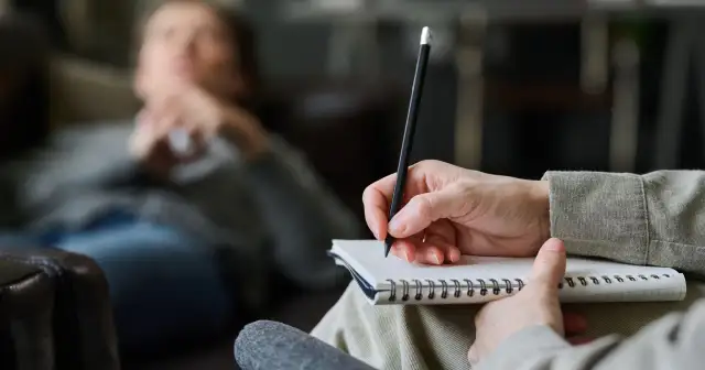 Psycholog słucha i notuje, pomagając pacjentowi zrozumieć siebie.