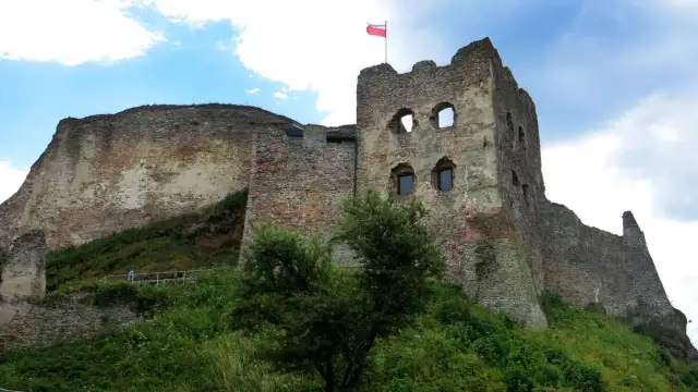 Zamek Czorsztyn, majestatyczne ruiny na wzgórzu, dumnie prezentuje polską flagę na tle błękitnego nieba.