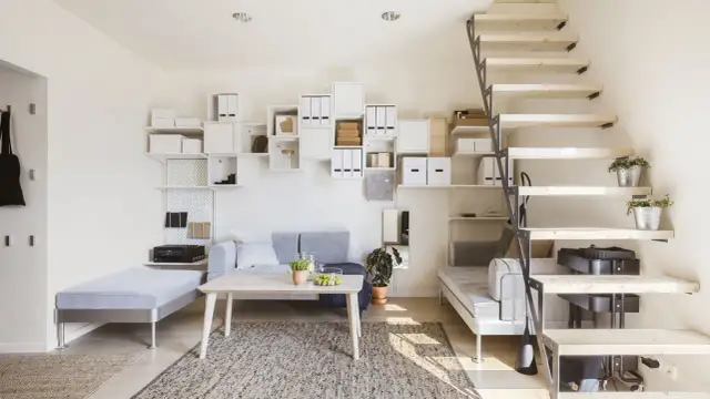 Nowoczesny dom samowystarczalny za 150 tys. z otwartą przestrzenią, schodami i mnóstwem białych półek.