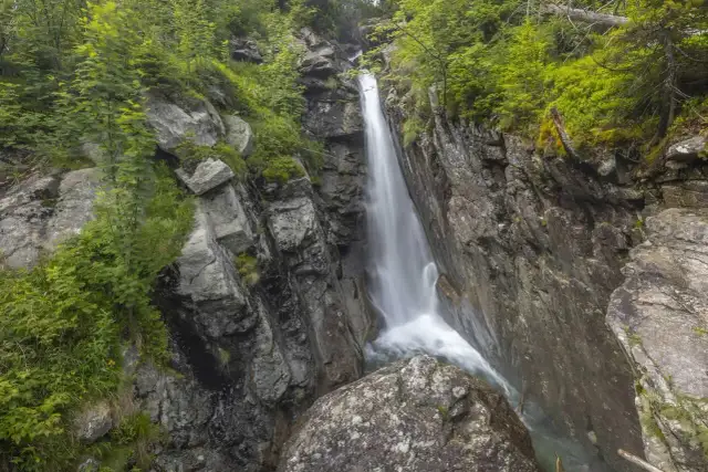 Wodospady na Słowacji w otoczeniu skalistych zboczy i bujnej zieleni. Woda spływa kaskadami po kamieniach.