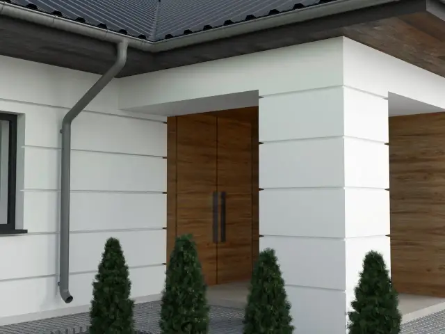 Nowoczesny dom z białymi boniami listwami elewacyjnymi, drewnianymi drzwiami i zielonymi tujami.