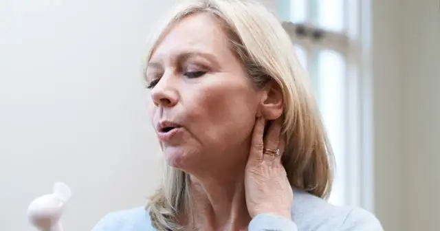 Kobieta z gorącą falą, szukająca sposobów, jak leczyć zaburzenia hormonalne. Używa małego wiatraczka.