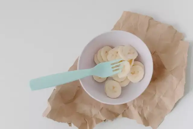 Miseczka z plasterkami banana i niebieskim widelcem. Czy królik może jeść banana? To pytanie nurtuje wielu właścicieli tych uroczych zwierząt.