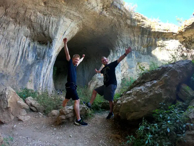 Dwóch mężczyzn cieszy się przy wejściu do jaskini Prohodna.