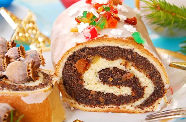 Pyszne ciasto z makiem, udekorowane kolorową posypką i lukrem. Obok leżą suche maki, sugerując świąteczny nastrój.