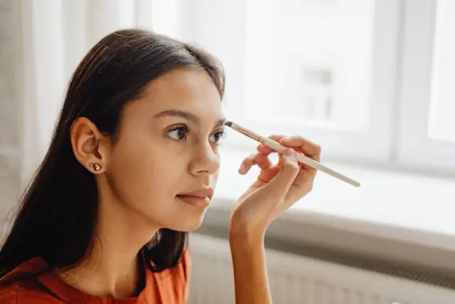 Dziewczyna aplikuje hennę do brwi. Różne rodzaje henny do brwi pozwalają na uzyskanie naturalnego efektu.